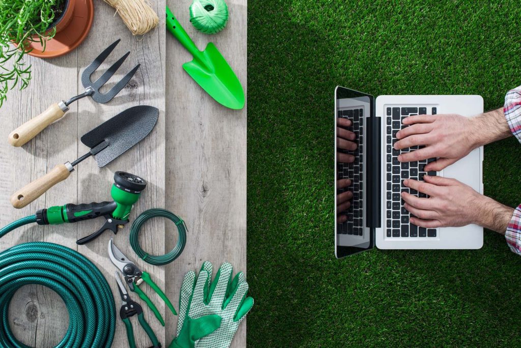 Gardening tools on a table and gardener networking with a laptop gardening and technology concept