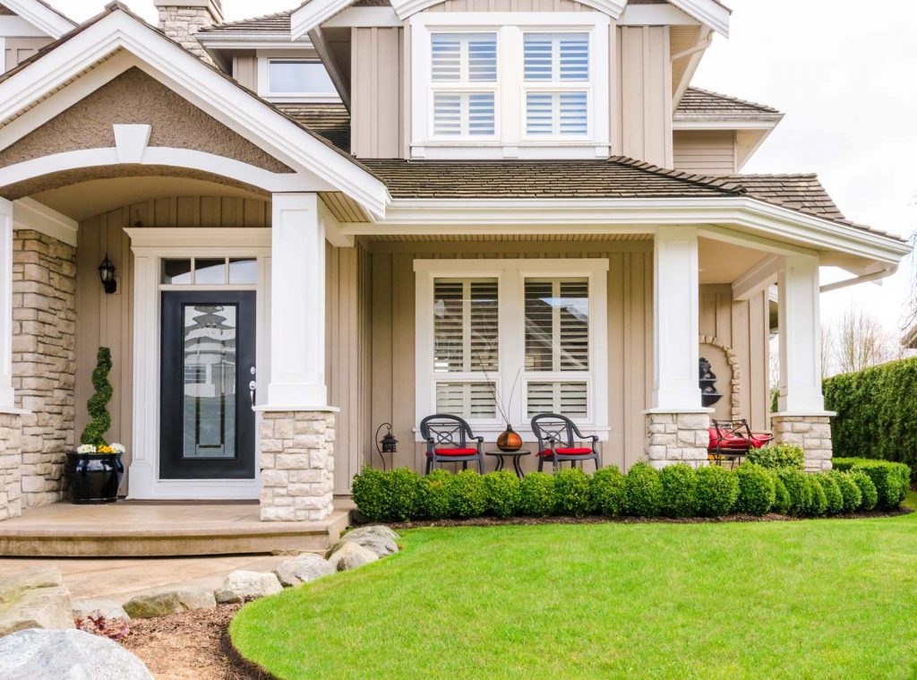 The entrance of a luxury house with a patio on a bright, sunny day.